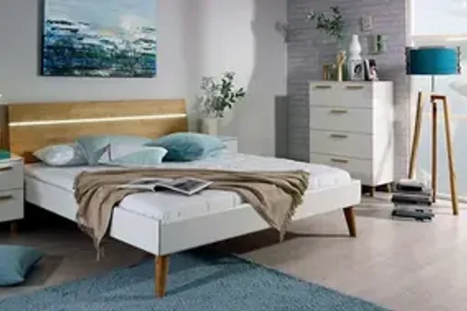 Rauch Mavi Extra Schlafzimmer mit Bett, beleuchtetem Kopfteil, Nachttisch und Kommode Helles Schlafzimmer mit Rauch Mavi Extra Bett, beleuchtetem Kopfteil, Nachttisch und Kommode in Weiß und Holz